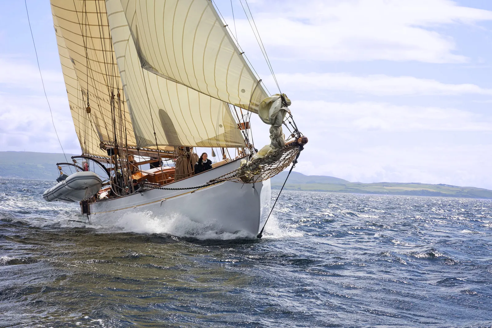 Fleet of historic sailing yachts at the Richard Mille Cup with the Island of Arran in the background