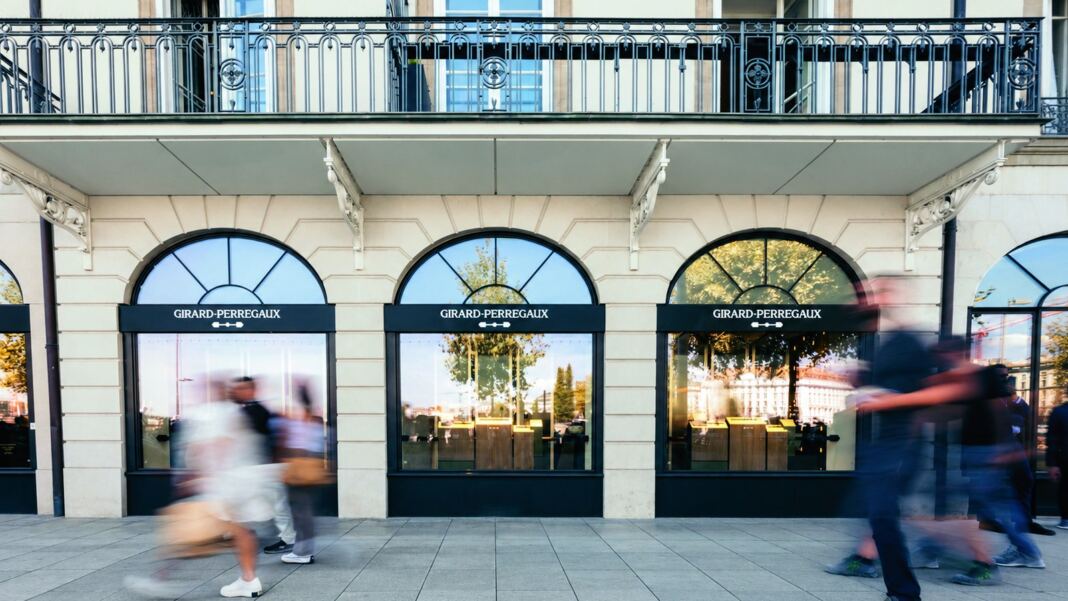 Girard-Perregaux maison on the Geneva lakefront with its balcony and three arche Girard-Perregaux maison on the Geneva lakefront with its balcony and three arched windows, passers-by in motion, official image