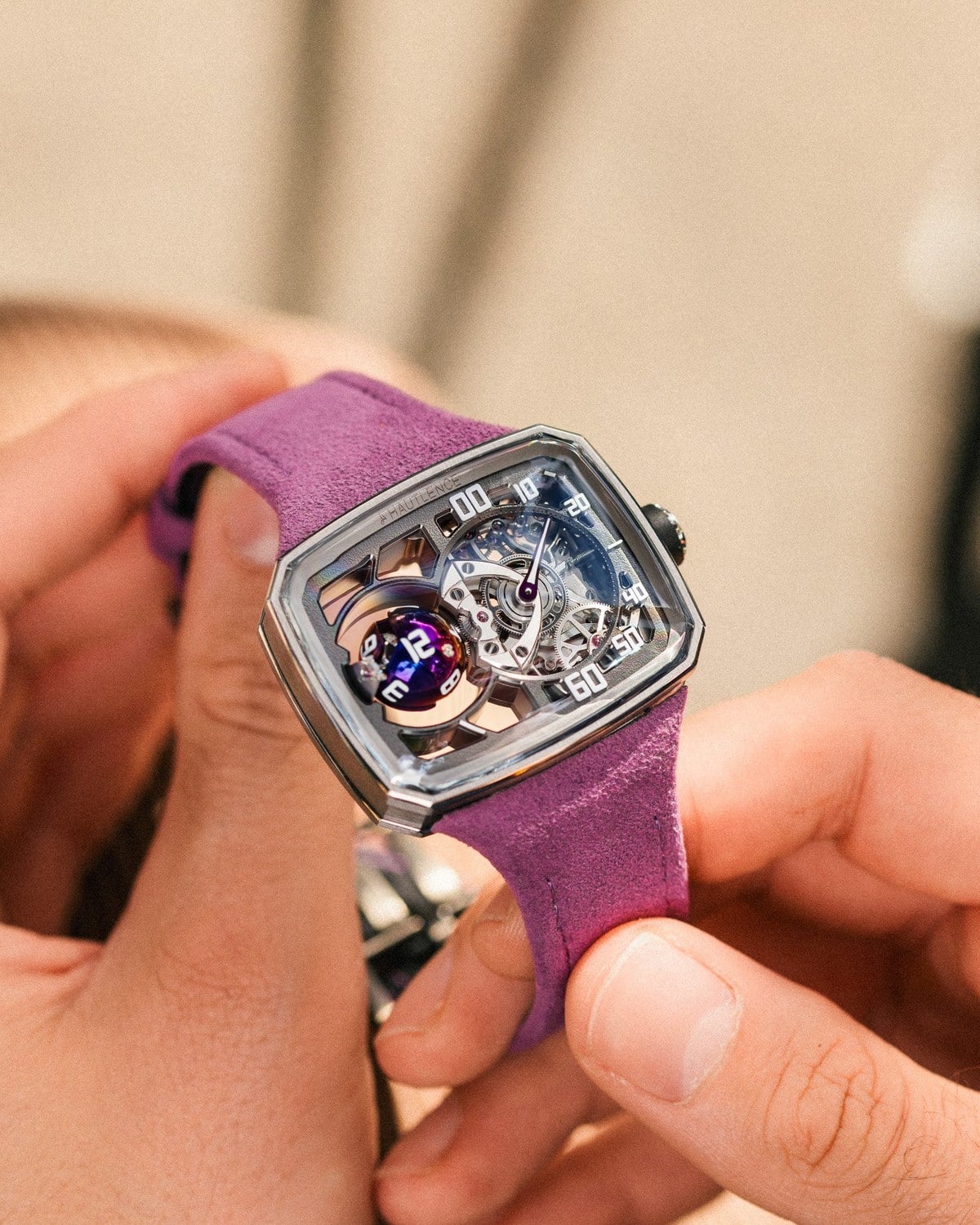 Hautlence Sphere Series 3 held in two hands on its purple strap, official image