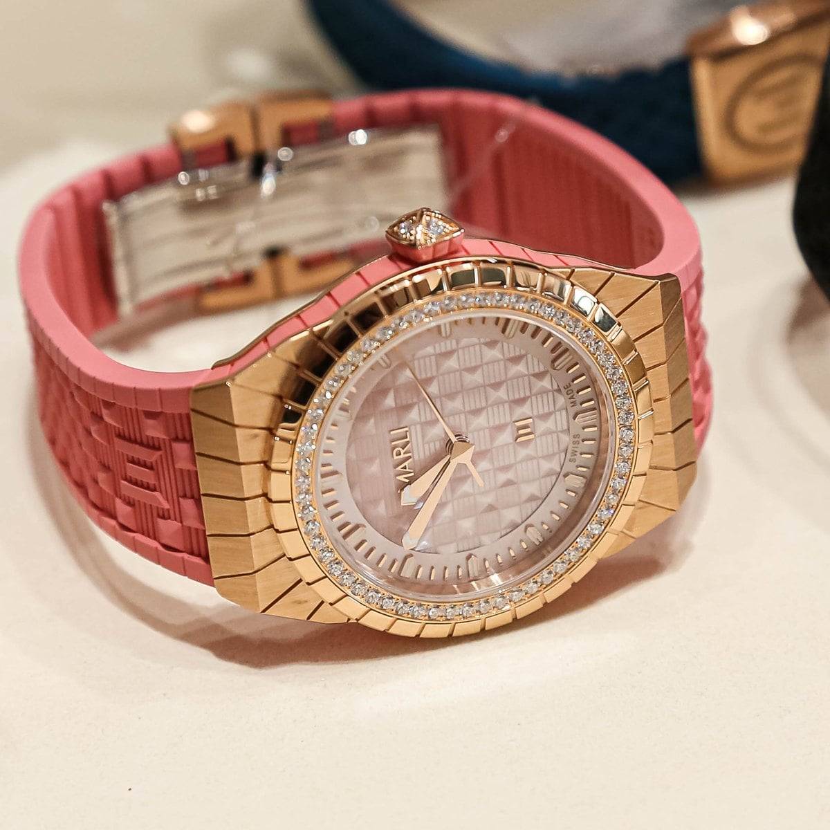 Marli timepiece in rose gold with diamonds on a pink strap, close-up of the pyramid mother-of-pearl dial