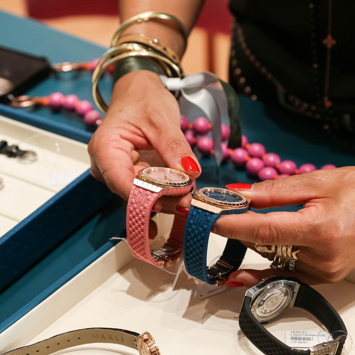 Marli timepiece in rose gold with a pink strap held in the hand with Marli jewellery