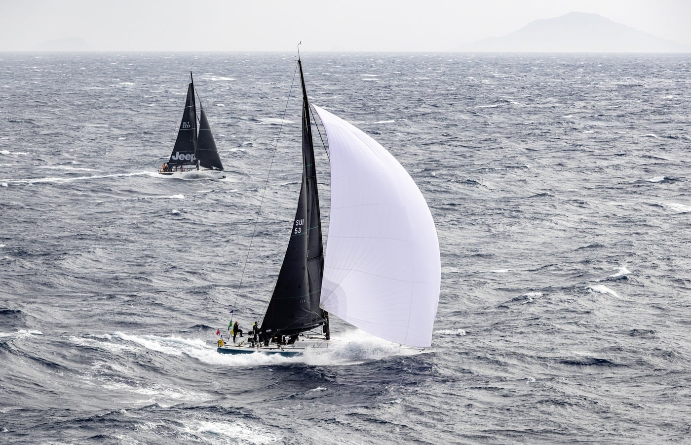A yacht under white spinnaker during the Rolex Middle Sea Race
